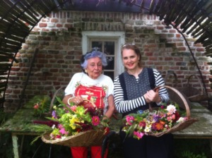 Mutter und Tochter stehen nebeneinander und haben beide einen Korb voller bunter Wiesenblumen zum Muttertag.