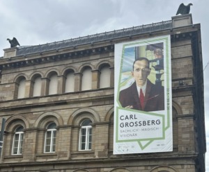 Man sieht die Gebäudefassade des Von der Heydt-Museums in Wuppertal mit einem großen Plakat der Ausstellung Carl Grossbergs.