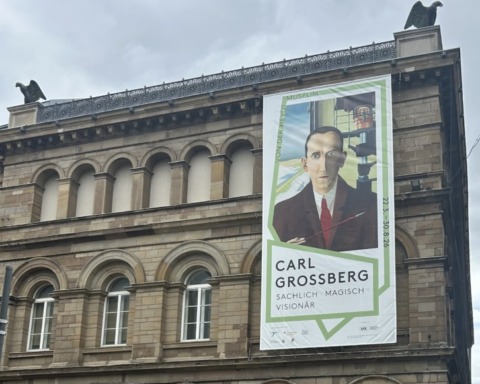 Man sieht die Gebäudefassade des Von der Heydt-Museums in Wuppertal mit einem großen Plakat der Ausstellung Carl Grossbergs.